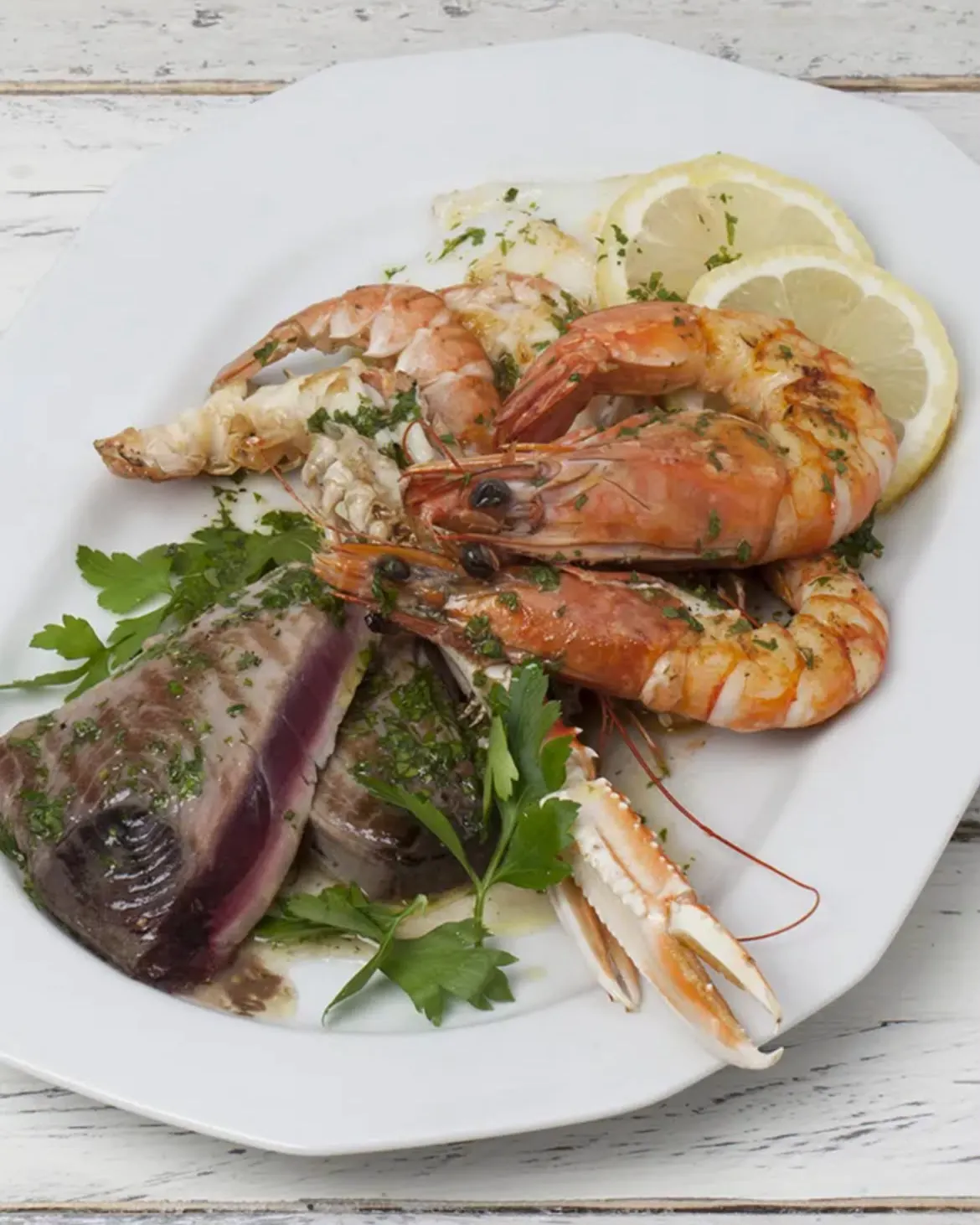 Teller mit Großgarnelen, Scampi und Thunfisch, mit Petersilie und Zitrone